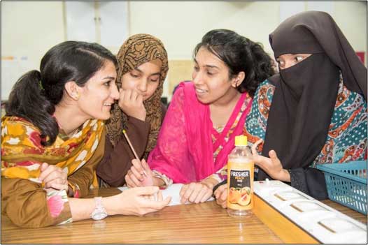 Four women at table at Post IYL inspired outreach at Quaid-i-Azam University