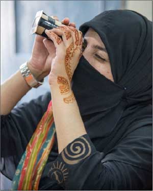 Woman looking through binoculars at Post IYL inspired outreach at Quaid-i-Azam University