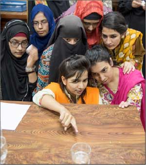 Women looking at glass at Post IYL inspired outreach at Quaid-i-Azam University